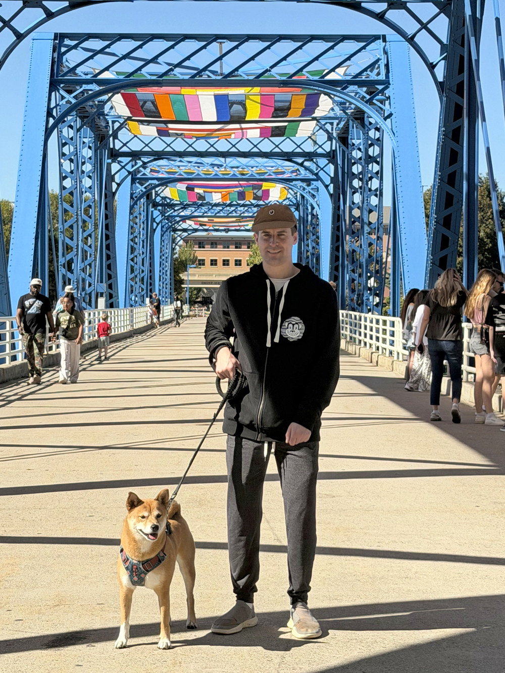 Bob Bice on a blue pedestrian bridge with his Shiba Inu on a leash